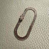 gold chain bracelet on a textured light gray surface