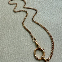 18k Gold antique watch chain necklace on a light gray textured surface