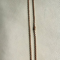 Long chain necklace on a textured light gray background