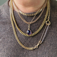 Gold chain necklace with a pendant on a brown sweater