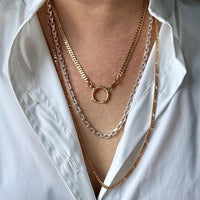Layered gold necklaces on a white shirt