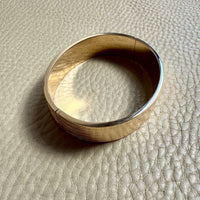 Gold bangle on a textured beige surface