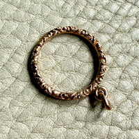 18k gold ring with intricate design on a textured light green background