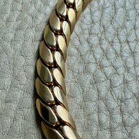 Gold chain bracelet on a textured light gray background