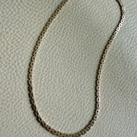 14k Gold vintage chain necklace on a textured gray background