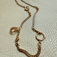 Gold chain necklace on a textured light gray background. PenelopePenelope.com