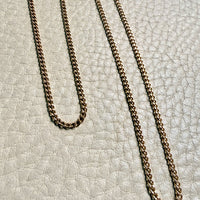 Gold chain necklace on a textured light gray surface