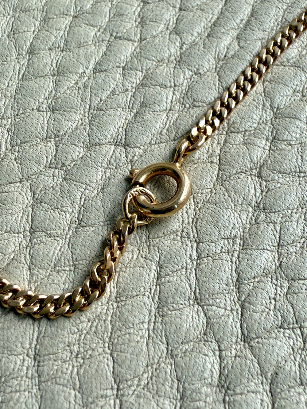 Gold chain necklace on a textured light gray surface