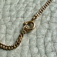 Gold chain necklace on a textured light gray surface