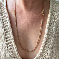 antique 18k gold Necklace worn by a person wearing a beige knit sweater