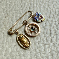 Gold charms with owl, pansy and wheel design on a textured surface