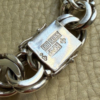 Close-up of a silver bracelet with a clasp on a beige textured background