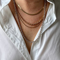 Person wearing multiple gold necklaces on a white shirt