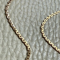 Gold virola link chain on a textured gray surface. Penelope Penelope Vintage 18k gold Fine Jewelry