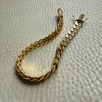 Gold chain bracelet on a textured light gray surface