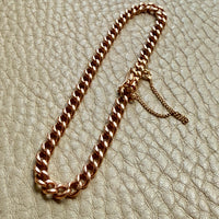 antique 18k Rose gold curb chain bracelet on a textured beige surface