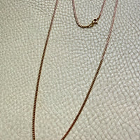 Gold chain necklace on a textured beige surface
