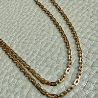 Gold chain necklace on a textured light green surface