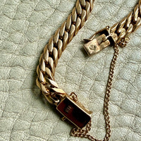 Gold chain bracelet on a textured light green surface