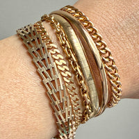 Gold bracelets on a wrist against a neutral background PenelopePenelope.com