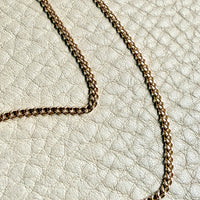 Gold chain necklace on a textured light gray surface