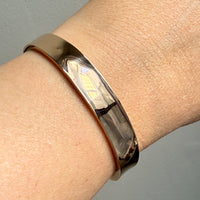 1960s era Vintage Danish 14k Gold Hinged Bangle Bracelet – 7 inch Interior Circumference on wrist over gray background