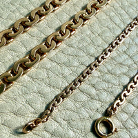 Two gold chains on a light green textured surface