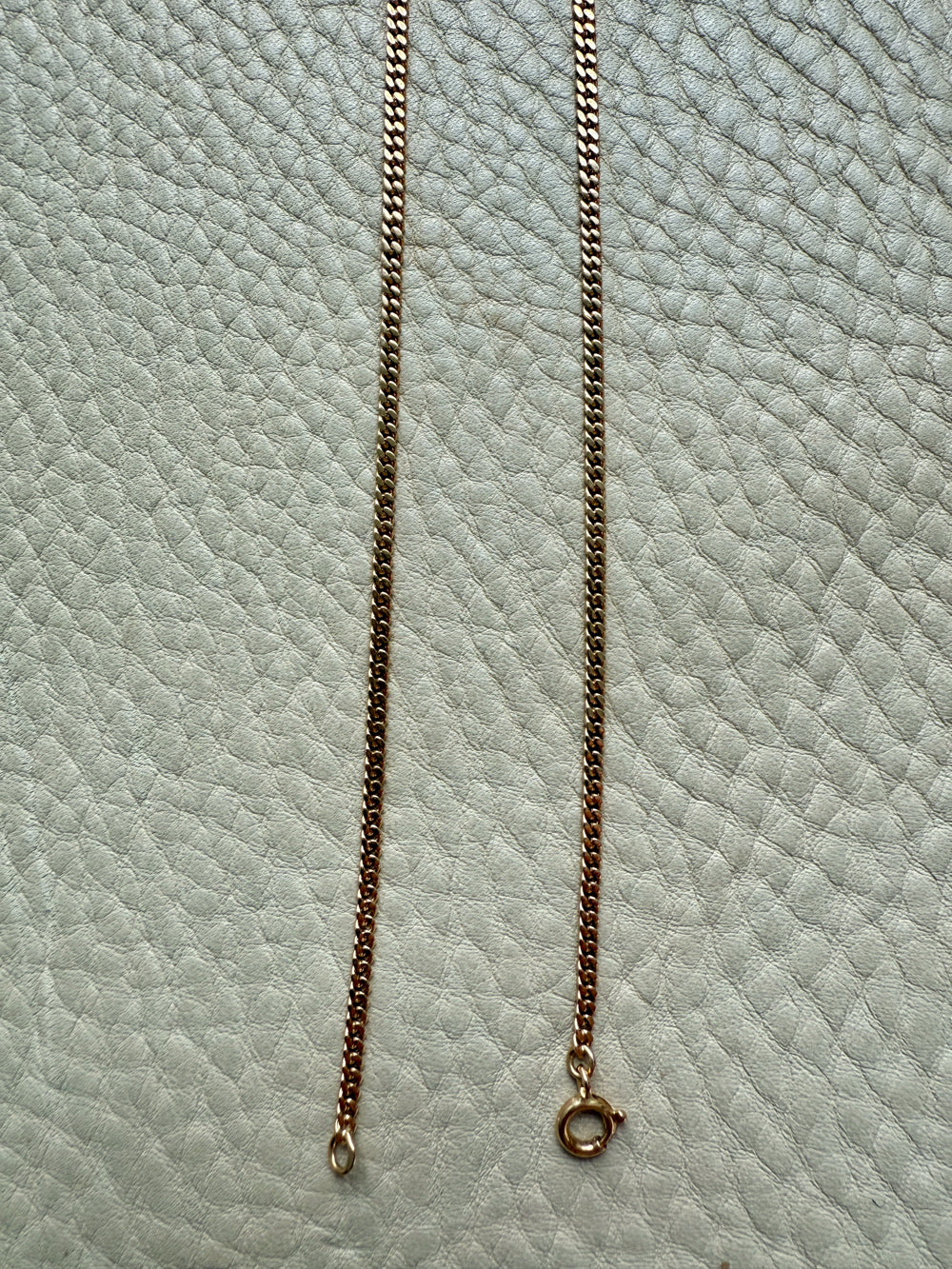 Gold chain necklace on a textured light blue surface