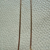 Gold chain necklace on a textured light blue surface
