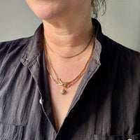 Person wearing a black shirt with layered gold necklaces