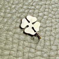 vintage 14k gold four-leaf clover charm on a textured light gray surface
