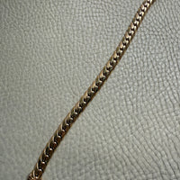 Gold chain bracelet on a textured gray surface