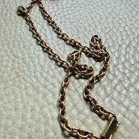 14k gold oval link Gold chain necklace on a textured light gray surface