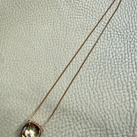 Necklace with a round pendant on a light gray textured background