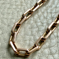 Gold chain bracelet on a textured light green surface