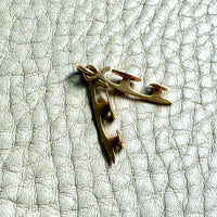 18k Gold ice skates pendant on a textured light gray background