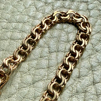 Gold chain bracelet on a textured light gray surface
