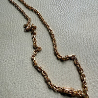 Gold chain necklace on a light gray textured surface. Penelope Penelope vintage gold jewelry