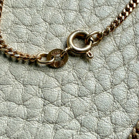 Gold chain necklace on a textured light gray surface