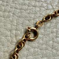 Gold chain necklace on a textured light gray background