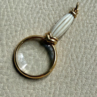 18k gold quizzing glass magnifying glass pendant on a textured light gray background