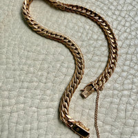 18k vintage Gold curb chain bracelet on a textured light gray surface penelopepenelope.com