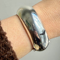 Silver donut bracelet on a wrist with a neutral background