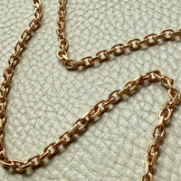 Gold chain necklace on a textured light green background penelopepenelope.com