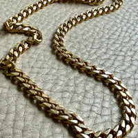 Gold chain necklace on a textured gray surface