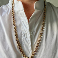 Person wearing a long 18k gold vintage rolo chain necklace with a white shirt.