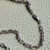 Silver chain necklace on a textured light green surface