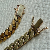 Gold chain bracelet on a textured light gray surface