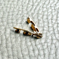 Gold ice skates charm on a textured gray surface