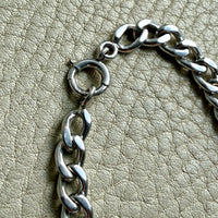 Close-up of a vintage 14k white gold chain on a textured beige surface